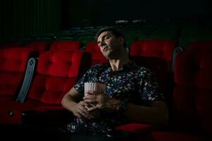 hombre caídas dormido mientras acecho película en cine y palomitas de maiz en mano, película carente interesante y aburrido. foto