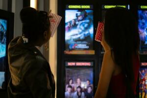 Both of young woman stand and watch the movie program to watch today. photo