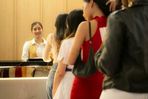 Young asian woman standing in line to buy movie tickets and in hand popcorn and drink, Smiling ticket salesman serving. photo