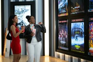 Both of young woman stand and watch the movie program to watch today. photo