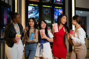 grupo de contento amigos acecho película en cine y comiendo palomitas de maiz a noche foto