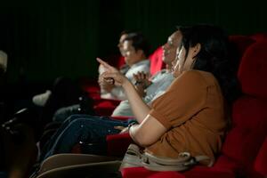 Asian mother and daughter watching movie in cinema. Family time concept. photo