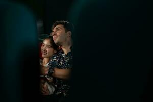 Young man and woman watching movie in cinema, sitting on red seats photo