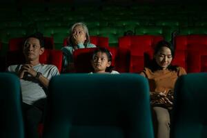 Asian mother and daughter watching movie in cinema. Family time concept. photo