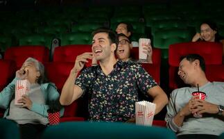 grupo de asiático mayor amigos acecho comedia película y risa a el cine con palomitas de maiz foto