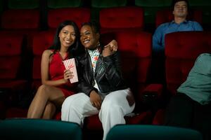 Both of young woman watching movie in cinema, sitting on red seats photo