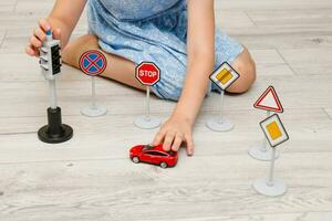 cute little girl playing at home on the floor with a road signs and traffic lights photo