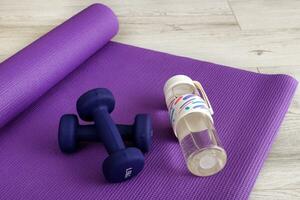 dumbbells and water bottle on gymnastic mat, fitness photo