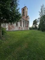 verde césped cerca el paredes de un antiguo abandonado iglesia, verano paisaje foto