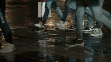 personas cruce el calle caminando en mojado la carretera en noche ciudad video