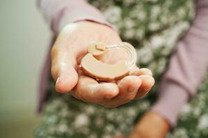 Asian senior woman patient using hearing aid in ear to reduce hearing loss problem. photo