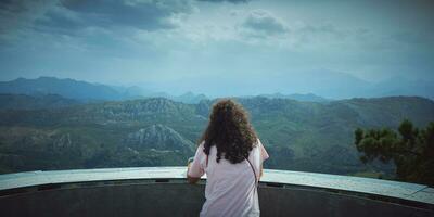 un mujer con Rizado pelo observa uno de el más hermosa paisajes en Asturias foto