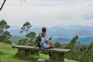 Serene mountain views. Young woman resting in the middle of nature eating a lollipop. photo