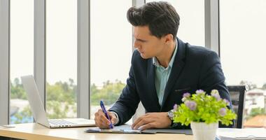 businessman using laptop and contemplating while working at his desk in the office. photo