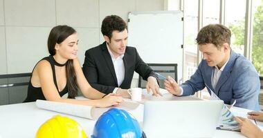 Diverse group of engineers, technicians, and specialists on meeting analyze technical drafts and hardhat presenting blueprint to business people in office photo