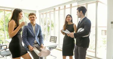 Diverse group of engineers, technicians, and specialists on meeting analyze technical drafts and hardhat presenting blueprint to business people in office photo