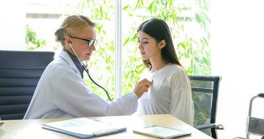 Asian woman patient sitting with doctor about her illness and showing x-ray results with blood pressure and heart rate measurement with stethoscope photo