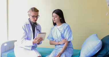 Asian woman patient sitting with doctor about her illness and showing x-ray results with blood pressure and heart rate measurement with stethoscope photo