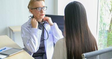 Asian woman patient sitting with doctor about her illness and showing x-ray results with blood pressure and heart rate measurement with stethoscope photo