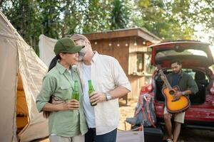 grupos de turistas bebiendo cerveza-alcohol y tocando la guitarra juntos con disfrute y felicidad en verano mientras acampan foto