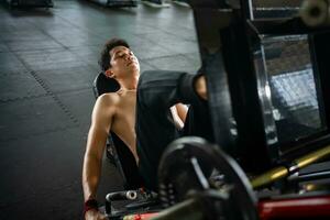 Asian men athletes doing leg press exercises with machines to strengthen muscles for health care at the gym stadium photo