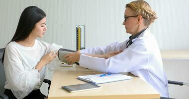 Asian woman patient sitting with doctor about her illness and showing x-ray results with blood pressure and heart rate measurement with stethoscope photo