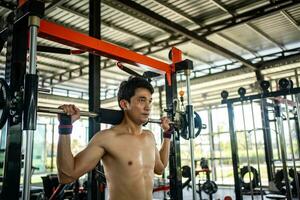 Man doing squat exercises with a barbell in gym photo