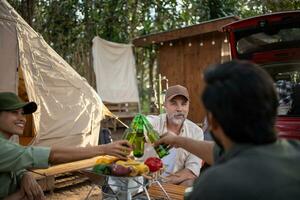 grupos de turistas bebiendo cerveza-alcohol y tocando la guitarra juntos con disfrute y felicidad en verano mientras acampan foto