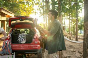 Men tourists drinking beer-alcohol and play guitar together with enjoy and happiness in Summer while camping photo