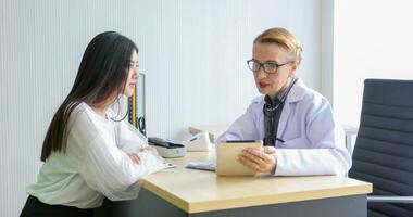 Asian woman patient sitting with doctor about her illness and showing x-ray results with blood pressure and heart rate measurement with stethoscope photo