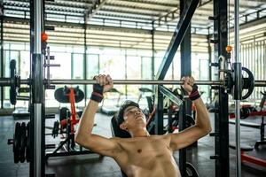 Man doing squat exercises with a barbell in gym photo