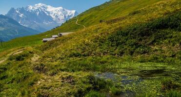 a mountain range with a pond and a small house photo