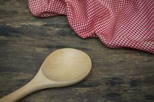 a wooden spoon and red gingham cloth on a wooden table photo