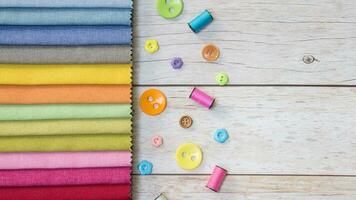 colorful fabric on wooden background with buttons and sewing thread photo