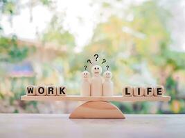 Wooden human figure with question marks. The choice between work and life. photo