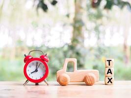 Red alarm, wooden blocks with the word TAX and  wooden toy car. The concept of paying tax for car. Car taxes. photo