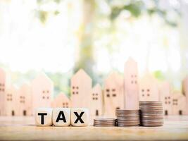 Wooden blocks with the word TAX and stack of coins, The concept of paying tax for house or property and car photo