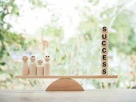 Wooden human figure and wooden blocks with the word SUCCESS on balancing scale for business success and winner concept photo