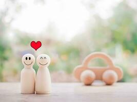 Wooden figure of happy couple with wooden toy car. The concept of happy family photo