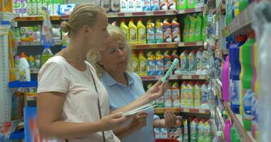 Dames kiezen huishouden wasmiddelen in de supermarkt video