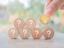 Close up hand arranging wooden block with light bulb and wooden block with question mark for leadership, creative, idea, innovation concept. photo