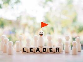 Wooden human figure with red flag standing on wooden block with word the LEADER. Leader teamwork power and confidnce, Successful team leader concept. photo