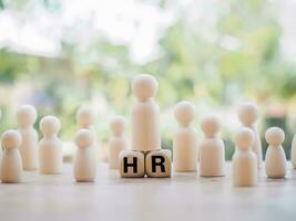 Wooden business figure standing on wooden block with word the HR. The concept of HR recruitment. Recruiting new workers. photo