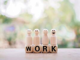 Wooden figure standing on wooden blocks with the word WORK. photo