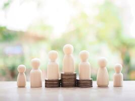 Wooden human figure on stack of coins for business concept photo