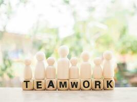 Wooden figure standing on wooden blocks with the word TEAMWORK, Successful team leader concept. photo