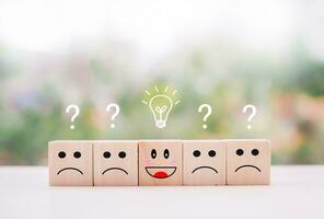 Emotion face wooden block with light bulb and question mark for leadership, creative, idea, innovation concept. photo