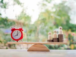 Red alarm and wooden human figure standing on stack of coins for saving concept. photo