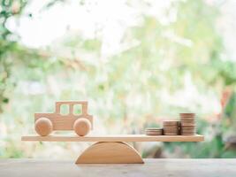 Wooden toy car and coins on balancing scale. The concept of saving money buy a car in the future. photo