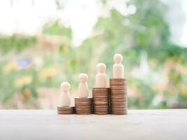 Wooden human figure on stack of coins for business concept photo